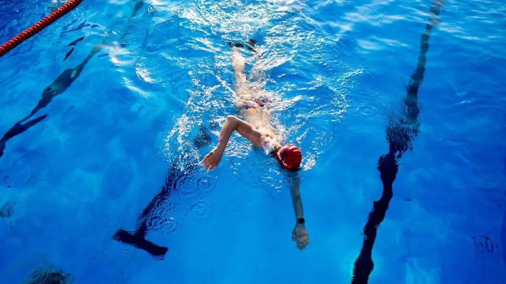 Eine-Frau-schwimmt-am-fruehen-Morgen-durch-ein-Becken-in-einem-Freibad