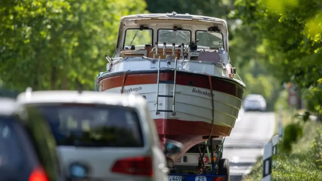 Ein-Motorboot-wird-auf-einem-Bootsanhaenger-durch-eine-Allee-Richtung-Ostsee-transportiert