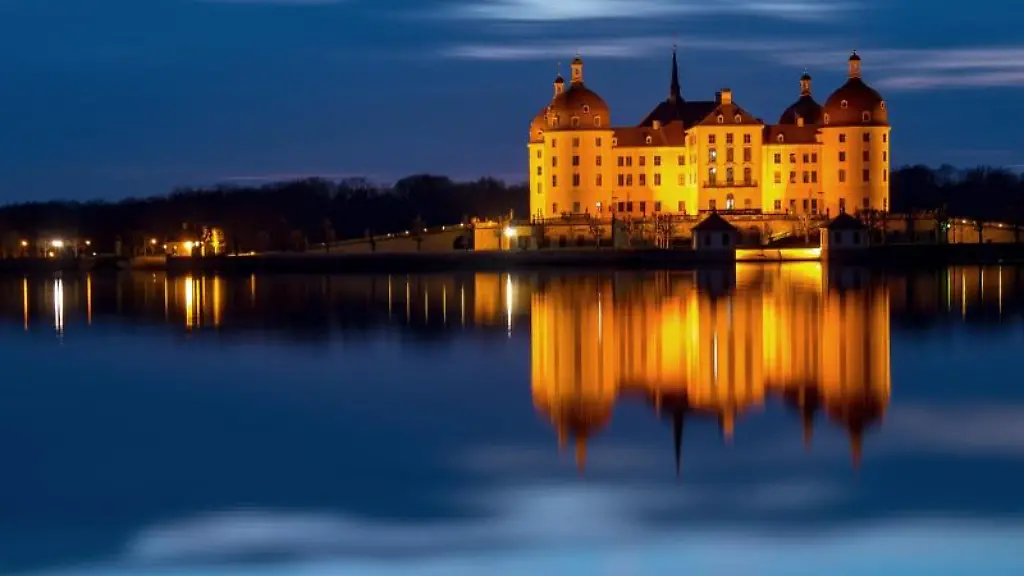 Das-beleuchtete-Schloss-Moritzburg-spiegelt-sich-am-Abend-im-Schlossteich