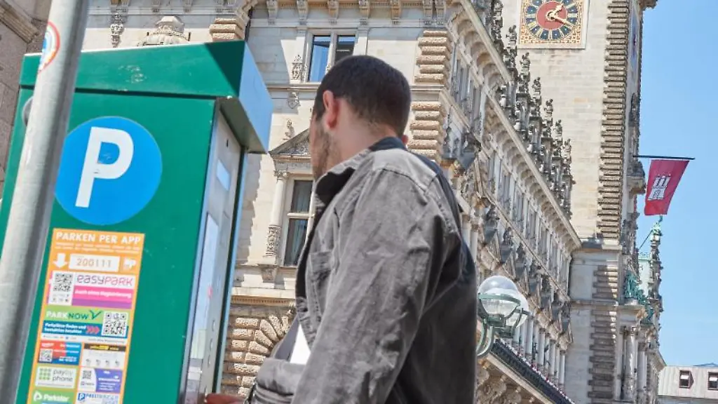 Ein-Mann-zieht-an-einem-Parkscheinautomaten-in-der-Innenstadt-einen-Parkschein