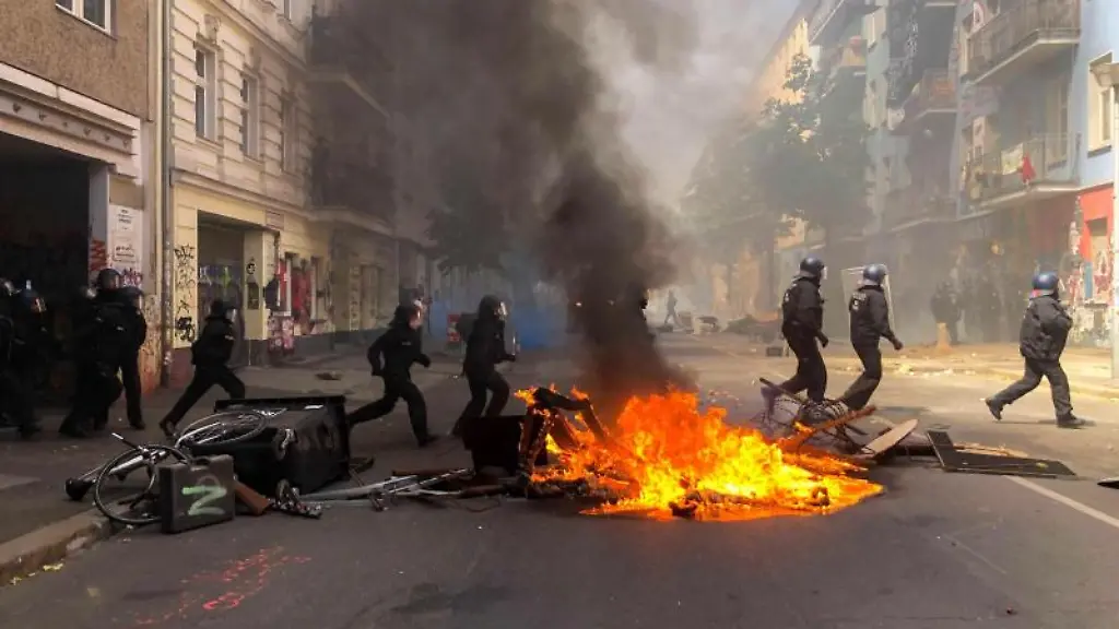 Polizisten-laufen-der-Rigaer-Strasse-in-Berlin-Friedrichshain-an-einer-brennenden-Barrikade-vorbei