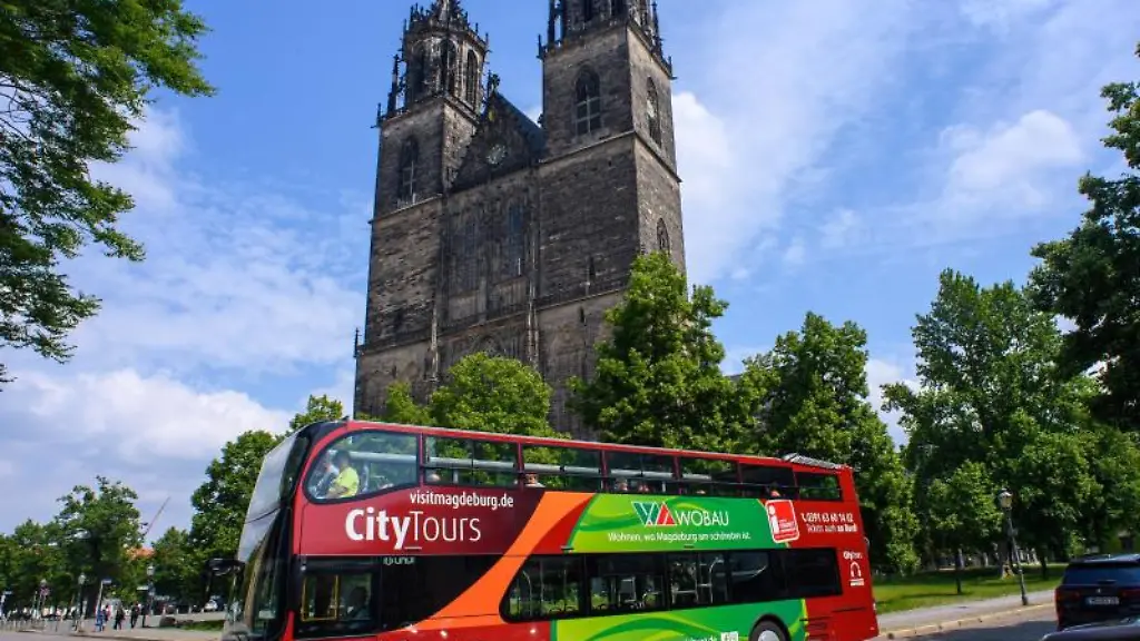 Ein-Doppeldeckerbus-einer-Stadtrundfahrt-faehrt-am-Dom-in-Magdeburg-vorbei