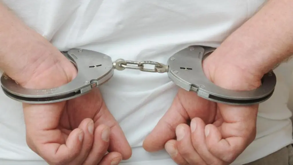 Zwei-maennliche-Haende-sind-in-Polizeihandschellen-gefesselt