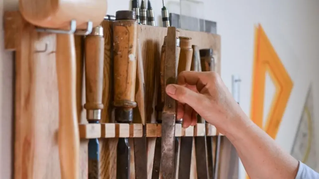 Ein-Handwerker-greift-in-einer-Papierwerkstatt-nach-einem-Werkzeug