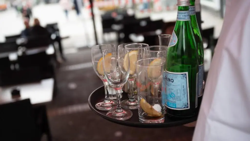 Ein-Kellner-raeumt-in-einem-Restaurant-einen-Tisch-ab