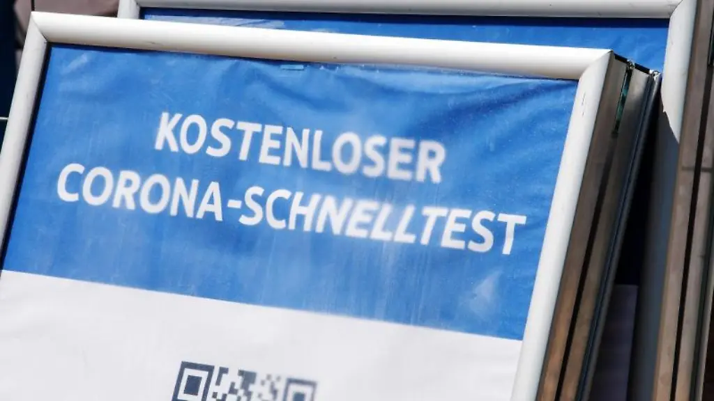 Ein-Schild-mit-der-Aufschrift-Kostenloser-Corona-Schnelltest-steht-vor-einem-Testzentrum