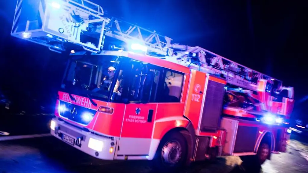 Ein-Drehleiterwagen-der-Feuerwehr-faehrt-mit-Blaulicht-zu-einem-Einsatz