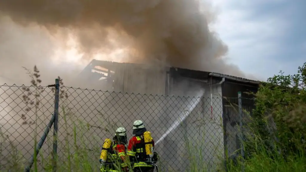 Feuerwehrleute-loeschen-eine-brennende-Lagerhalle-auf-dem-Gelaende-eines-Entsorgungsbetriebes