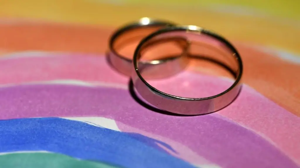 Zwei-Eheringe-liegen-auf-einer-gemalten-Regenbogenfahne