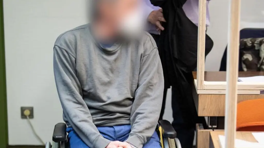 Ein-wegen-Mordes-Angeklagter-der-seinen-Transporter-in-den-Gegenverkehr-gesteuert-und-so-einen-Autofahrer-getoetet-haben-soll-sitzt-zum-Prozessauftakt-im-Rollstuhl-in-einem-Gerichtssaal-vom-Landesgericht-Muenchen-II