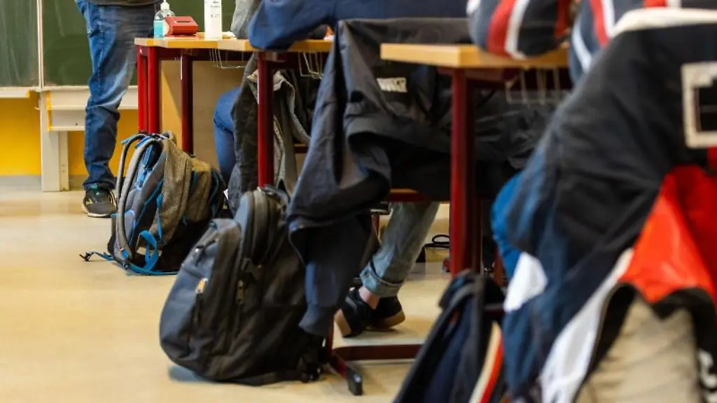 Rucksaecke-stehen-neben-den-Tischen-an-denen-die-Schuelerinnen-und-Schueler-beim-Unterricht-in-ihrer-Klasse-sitzen
