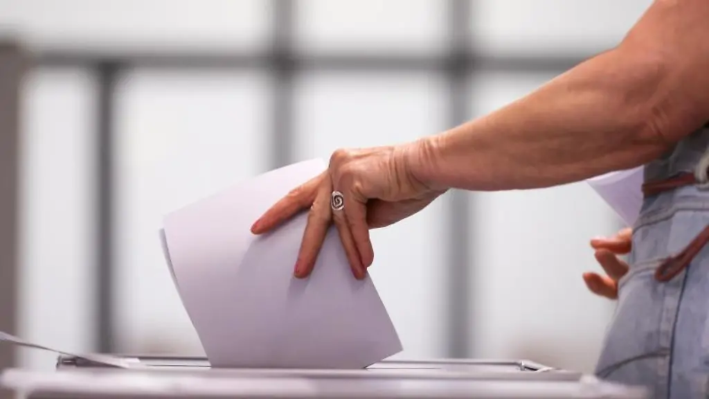 Eine-Frau-wirft-ihren-Stimmzettel-in-eine-Urne-in-einem-Wahllokal