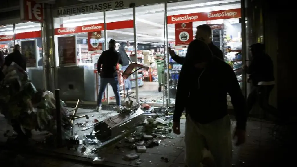 Menschen-stehen-vor-einem-gepluenderten-Geschaeft-in-der-Marienstrasse