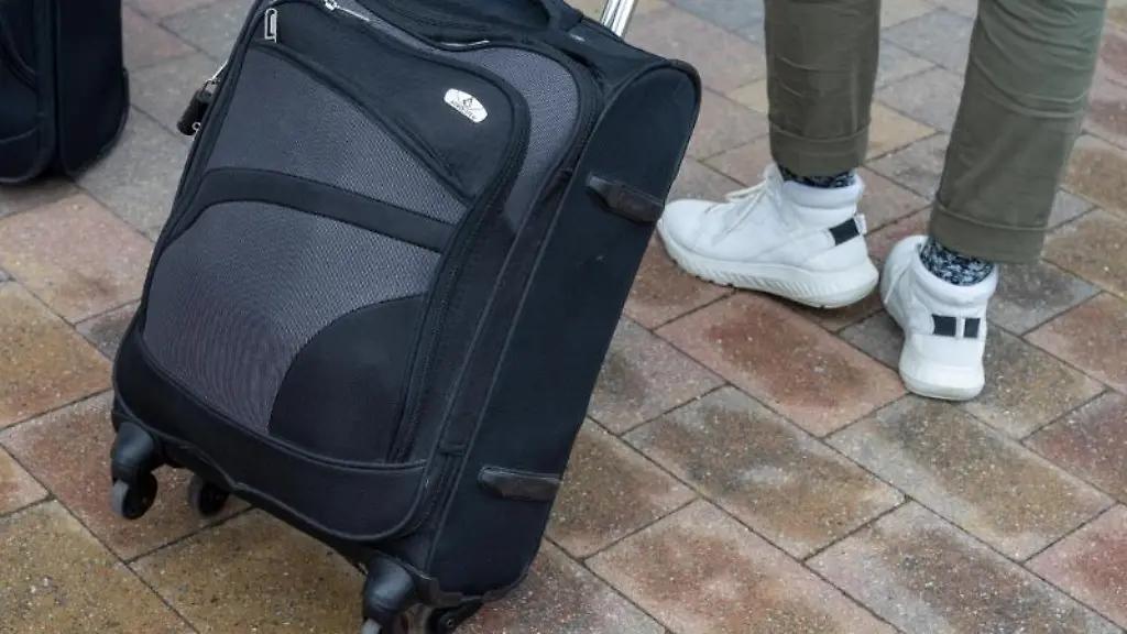 Reisende-gehen-mit-ihren-Koffern-ueber-die-Strasse