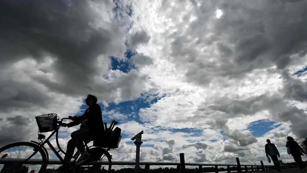 Ein-dramatischer-Wolkenhimmel-bietet-sich-den-Spaziergaengern-und-Radfahrern-auf-der-Promenade-am-Rheinufer