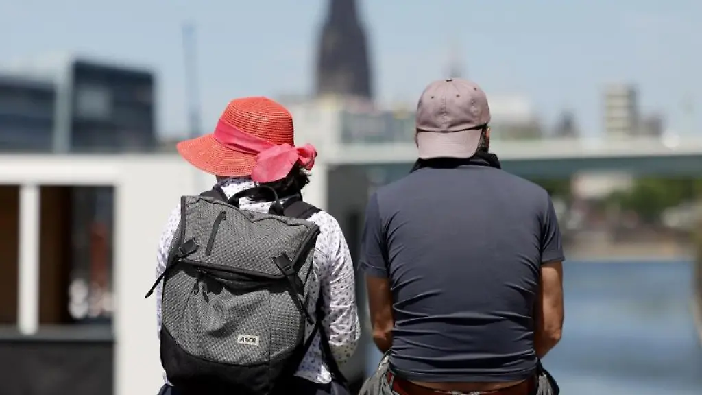 Ein-Mann-und-eine-Frau-sitzen-am-Rheinauhafen-in-Koeln-in-der-Sonne