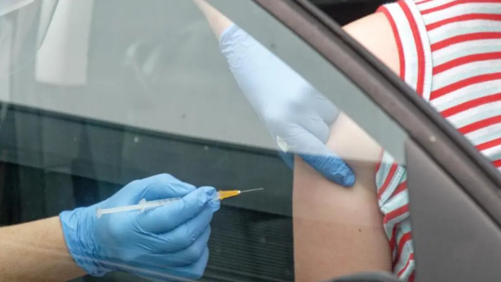 Ein-Mitarbeiter-spritzt-eine-Dosis-Impfstoff-in-den-Arm-einer-Frau-die-in-einem-Auto-sitzt