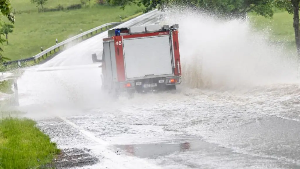 Ein-Fahrzeug-der-Feuerwehr-faehrt-auf-einer-Strasse-die-nach-einem-starken-Gewitter-ueberflutet-ist