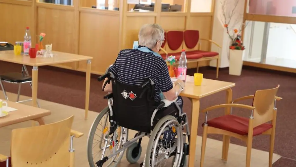 Ein-Heimbewohner-sitzt-in-einem-Rollstuhl-an-einem-Esstisch