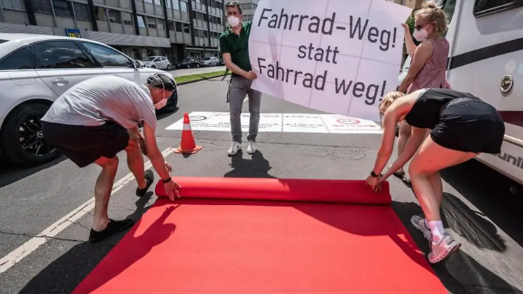 Aktivisten-rollen-einen-roten-Teppich-als-Pop-Up-Radweg-aus