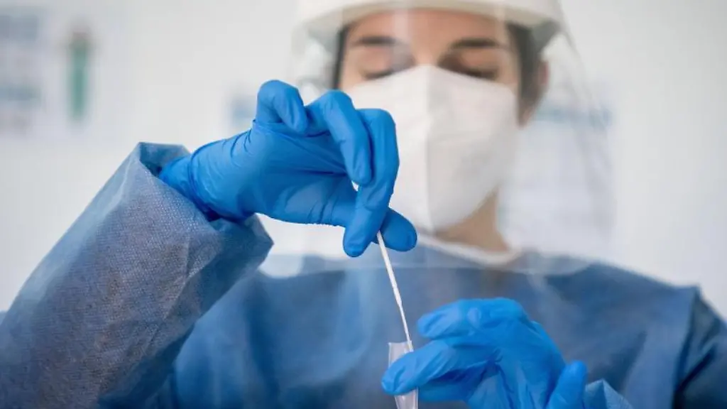 Medizinisch-geschultes-Personal-legt-das-Wattestaebchen-von-einem-Corona-Schnelltest-in-eine-Loesung