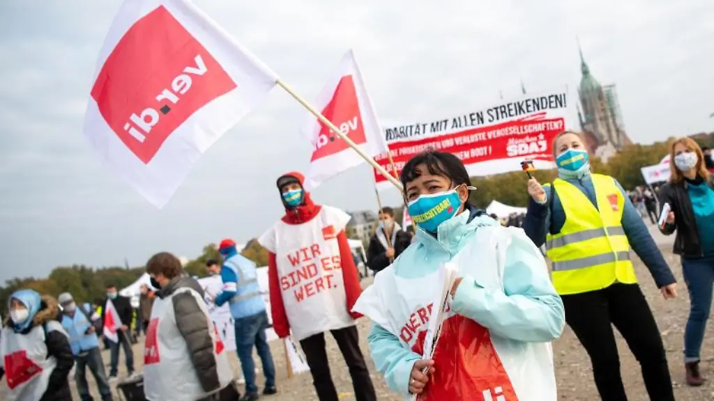 Eine-Demonstrationsteilnehmerin-haelt-eine-Verdi-Fahne-in-der-Hand