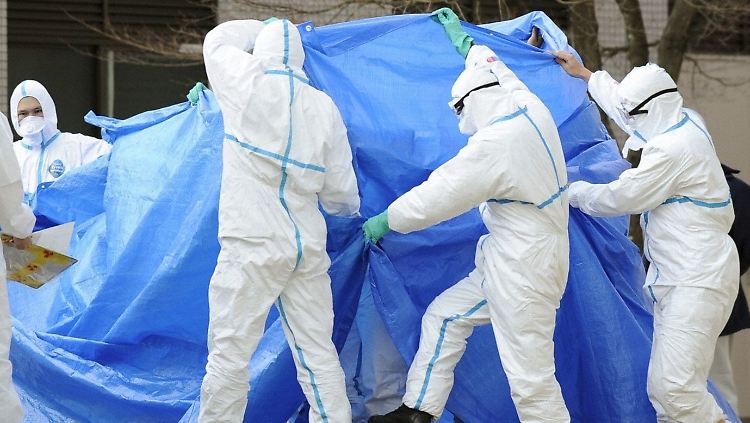 Rettungskräfte schirmen die beiden Männer, die Verbrennungen an den Füßen haben, ab.