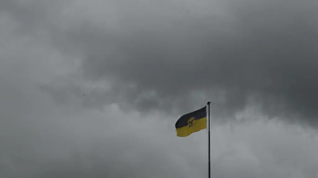 Dunkle-Regenwolken-ueber-dam-Neuen-Schloss-auf-dem-die-Flagge-von-Baden-Wuerttemberg-weht