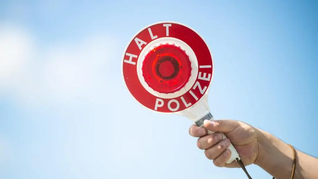 Ein-Polizist-haelt-eine-Polizeikelle-in-die-Hoehe