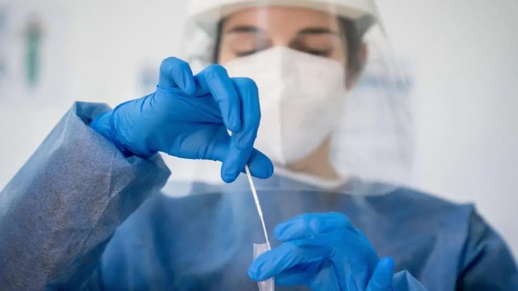 Medizinisch-geschultes-Personal-legt-das-Wattestaebchen-von-einem-Corona-Schnelltest-in-eine-Loesung