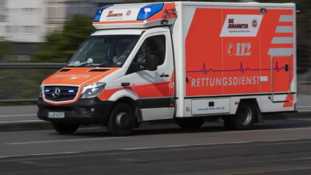 Ein-Rettungswagen-faehrt-mit-Blaulicht-ueber-eine-Strasse