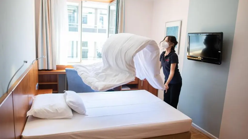 Eine-Frau-macht-in-einem-Hotelzimmer-das-Bett