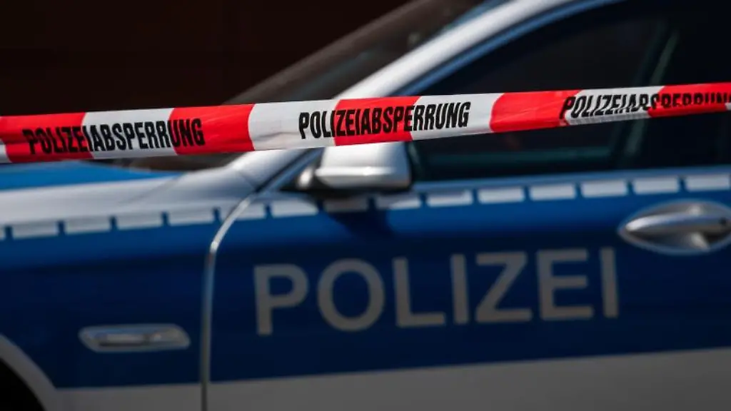 Ein-Polizeiauto-steht-hinter-einem-Absperrband-der-Polizei