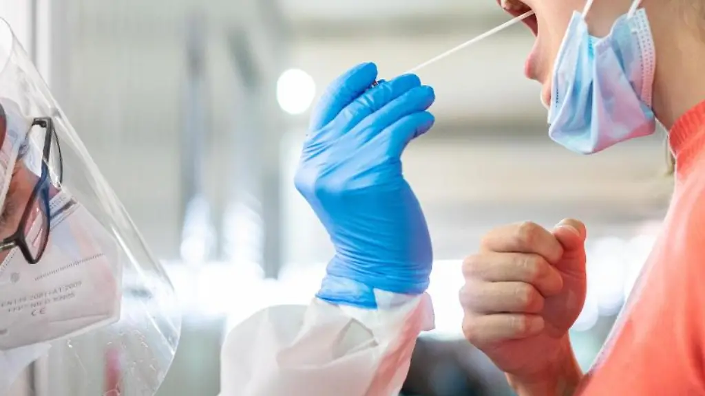 Ein-medizinischer-Mitarbeiter-entnimmt-einer-Frau-einen-Abstrich-fuer-einen-Corona-Test
