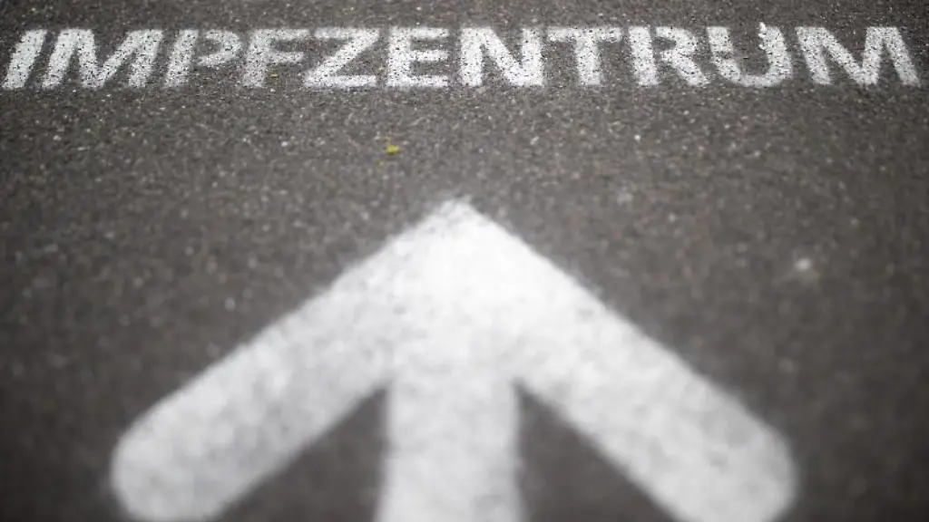 Der-auf-den-Boden-aufgespruehte-Schriftzug-Corona-Impfzentrum-weist-den-Weg-auf-dem-Messegelaende