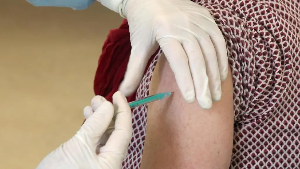 Eine-Frau-laesst-sich-in-einer-Praxis-den-Comirnaty-Impfstoff-injizieren