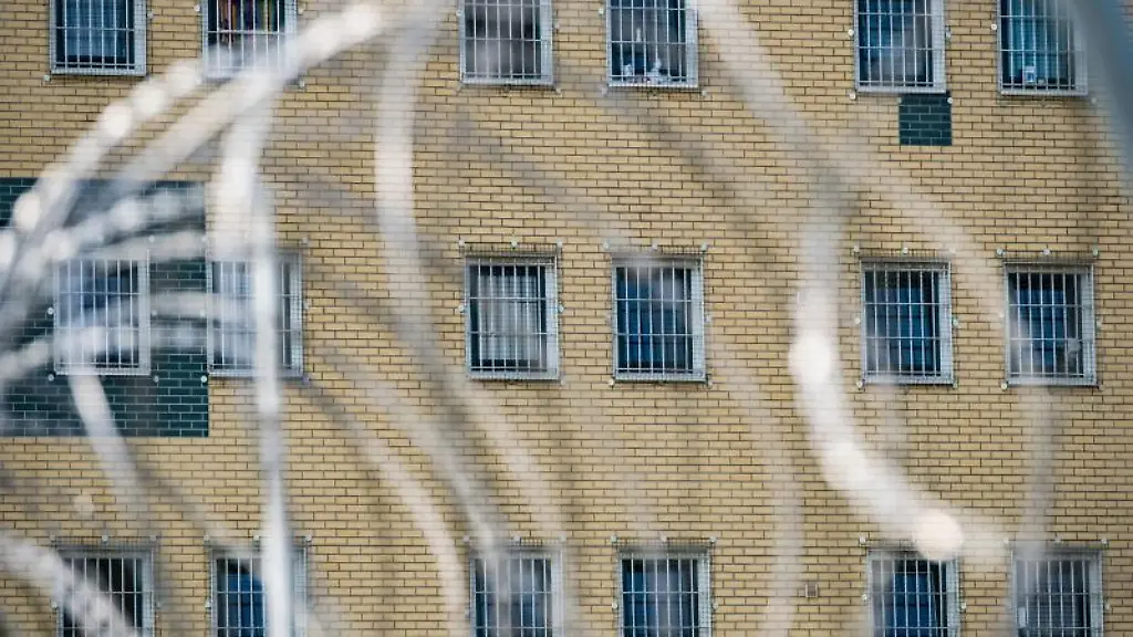 Blick-durch-den-Stacheldrahtzaun-vor-einer-Justizvollzugsanstalt