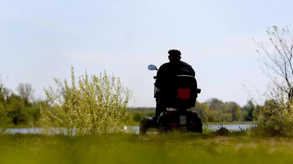 Ein-aelterer-Mann-sitzt-auf-seinem-Elektromobil-im-Stadtpark