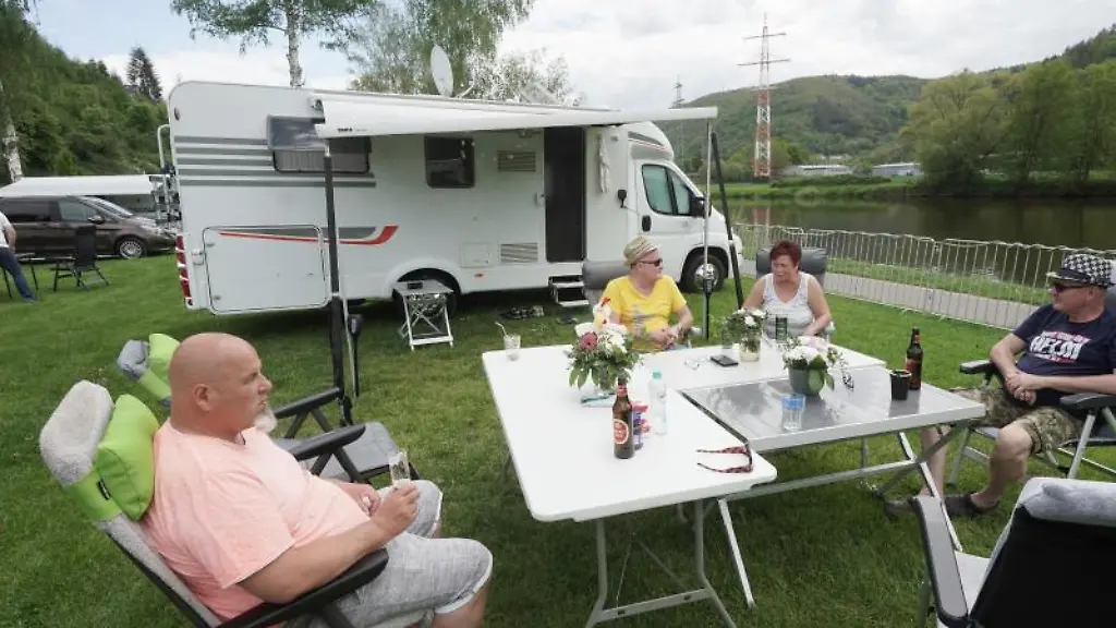 Camper-sitzen-vor-ihrem-Wohnmobil-in-der-Sonne