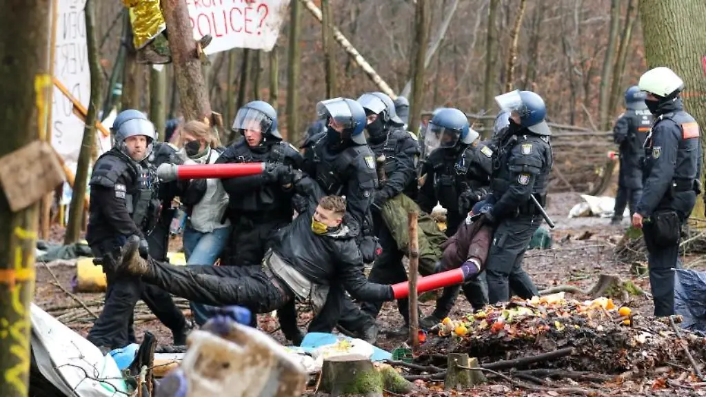 Polizisten-tragen-drei-Aktivisten-die-ihre-Arme-in-Metallrohre-gesteckt-und-sich-so-miteinander-verbunden-haben-aus-dem-letzten-verbliebenen-Camp-im-Dannenroeder-Forst
