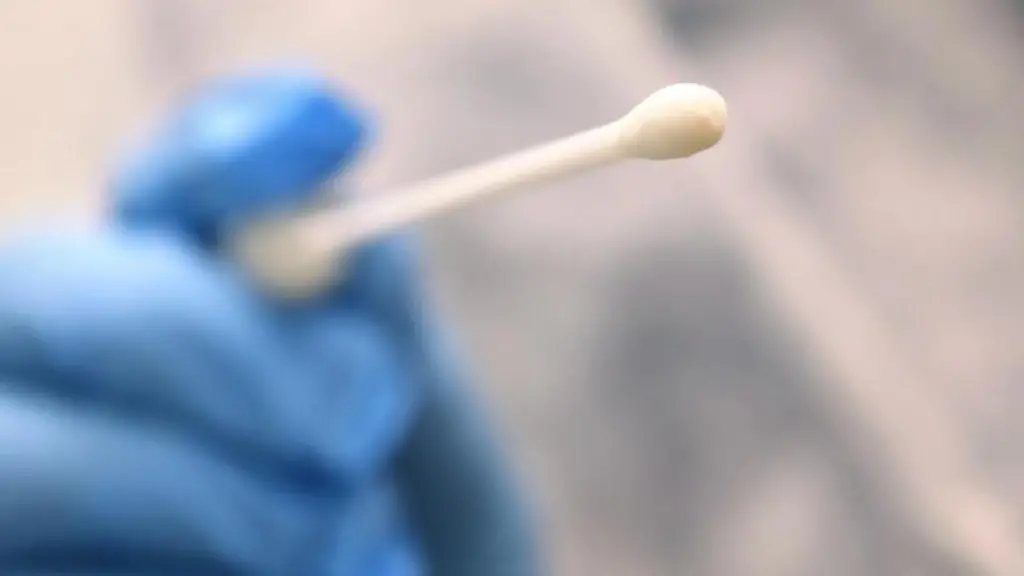 Ein-Arzt-haelt-einen-Tupfer-mit-dem-ein-Abstrich-fuer-einen-Coronatest-gemacht-wird