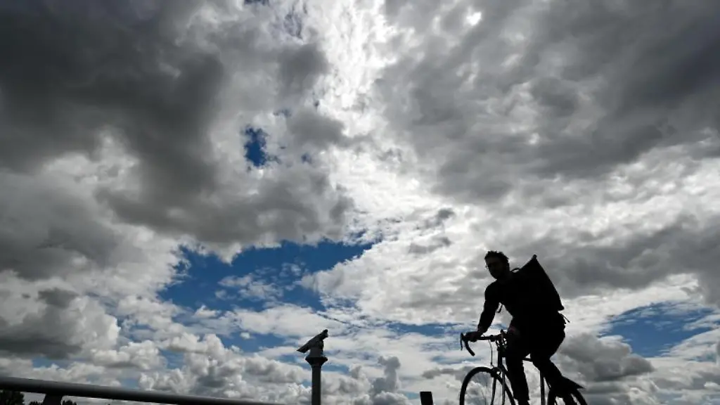 Ein-Radfahrer-ist-bei-dramatischer-Bewoelkung-auf-der-Promenade-am-Mainzer-Rheinufer-unterwegs