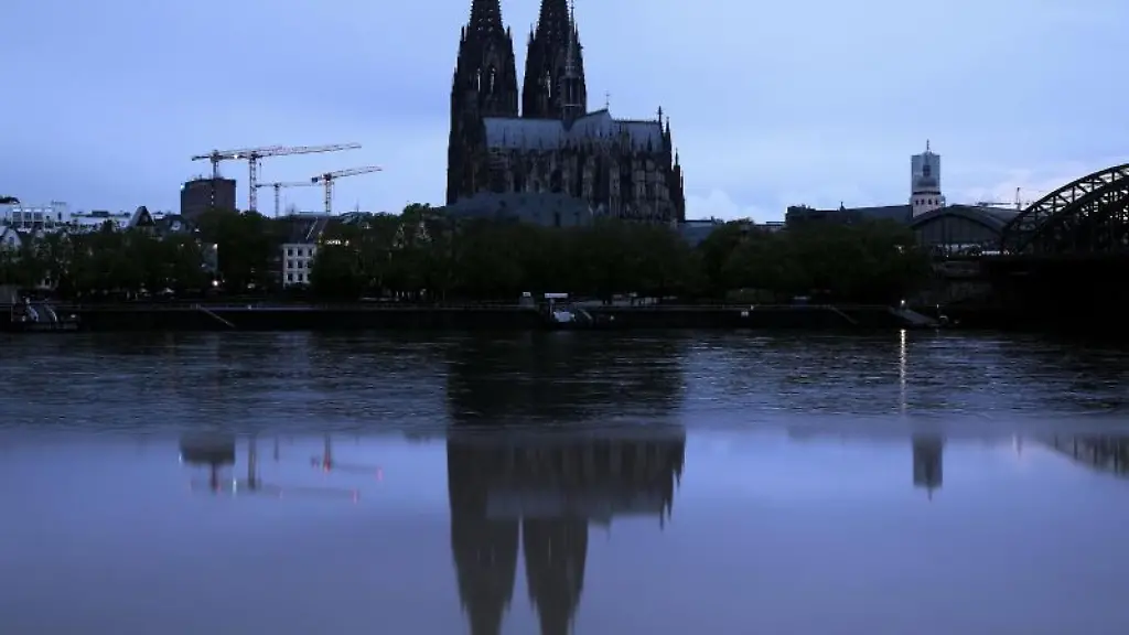 Der-Koelner-Dom-spiegelt-sich-am-Morgen-in-einer-Pfuetze