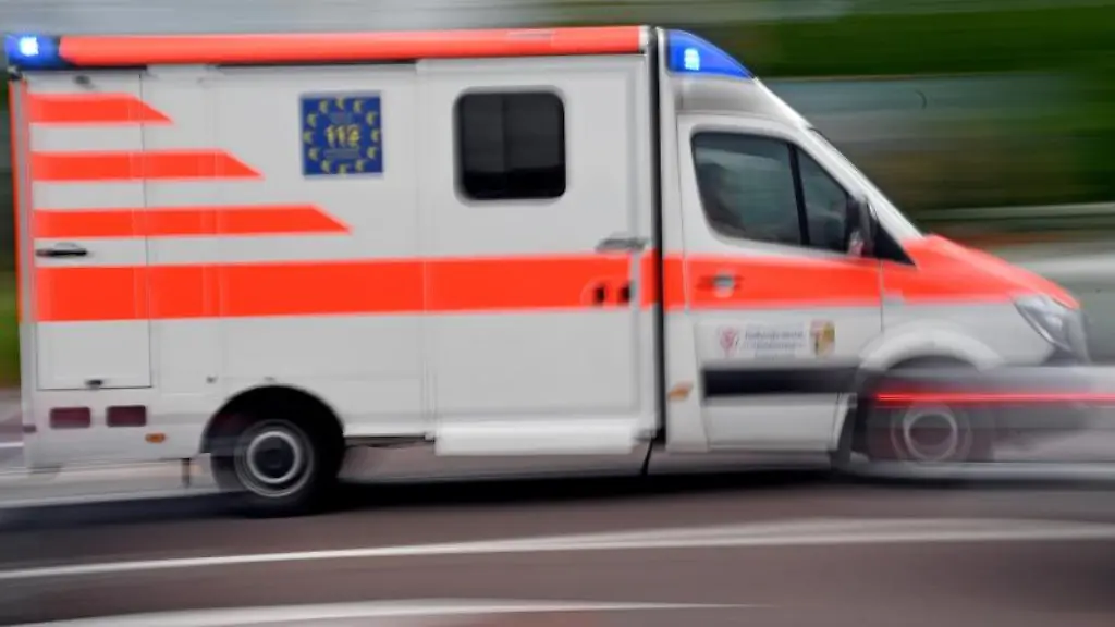 Ein-Krankenwagen-faehrt-mit-Blaulicht-auf-einer-Strasse