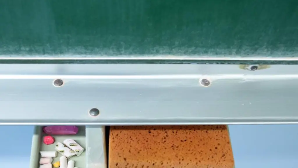 Schwamm-und-Kreide-liegen-in-einem-Klassenraum-unter-einer-Tafel