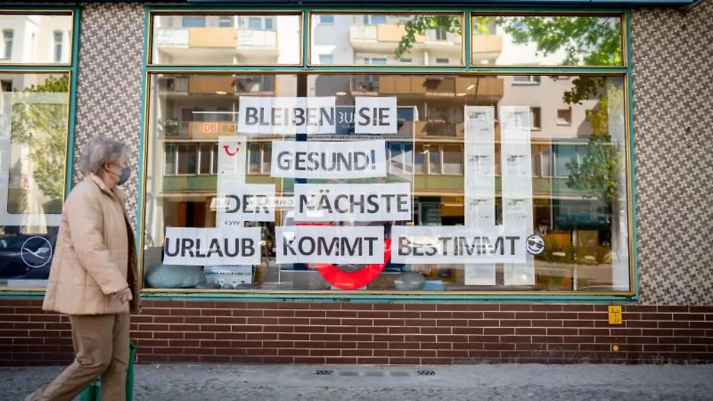 Eine-Passantin-mit-Maske-geht-an-einem-Reisebuero-vorbei