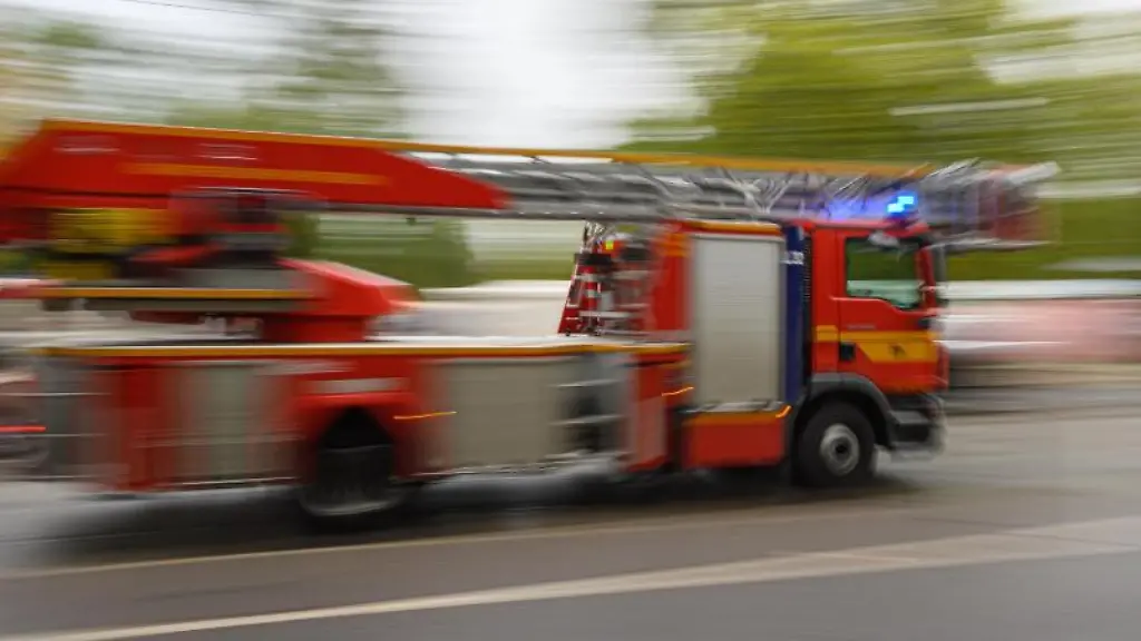 Ein-Feuerwehrfahrzeug-mit-Drehleiter-faehrt-zu-einem-Einsatz