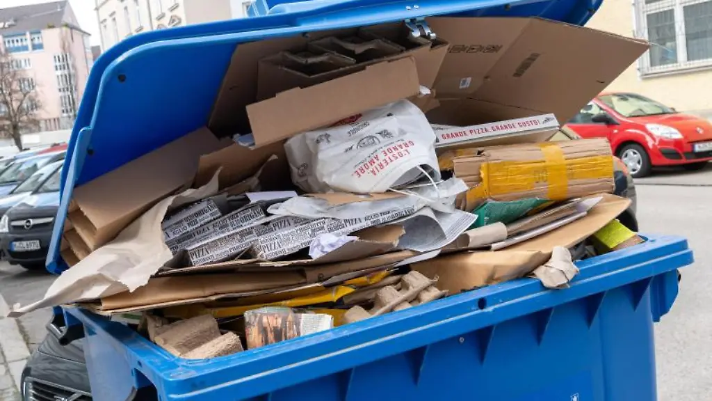 Eine-uebervolle-Papier-Muelltonne-steht-in-einer-Strasse