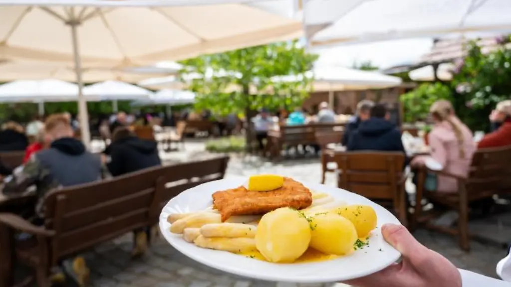 Ein-Kellner-haelt-in-einem-Restaurant-einen-Teller-mit-einem-Spargelgericht