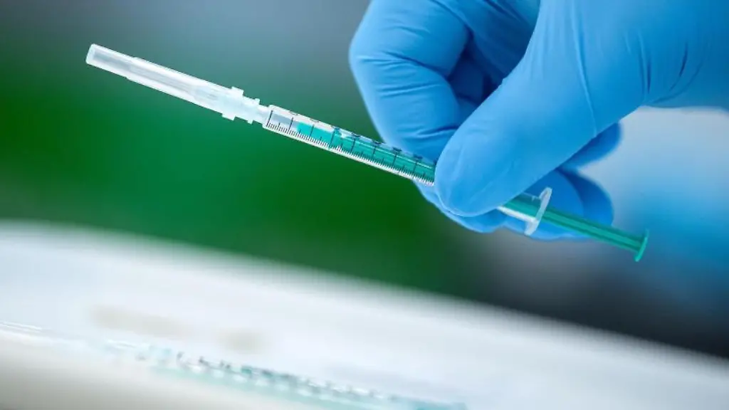 Ein-Mitarbeiter-eines-Impfzentrums-haelt-eine-Spritze-in-der-Hand